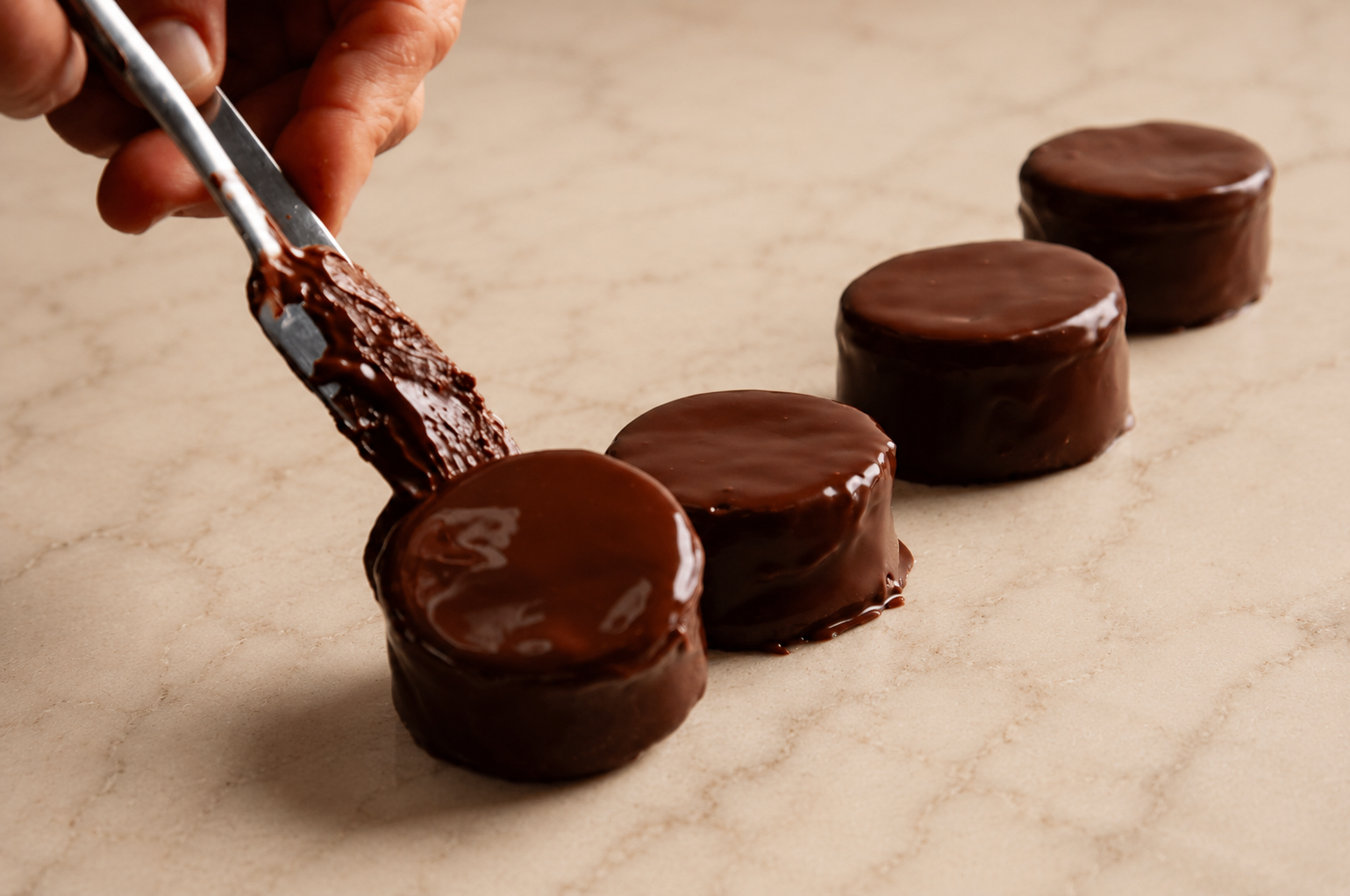 Proceso artesanal del bañado de alfajores de chocolate negro
